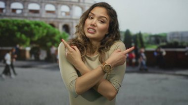 İspanyol kadın kollarını kavuşturuyor ve kolezyum binasında her iki tarafı işaret ediyor; karışıklık ikilemi.