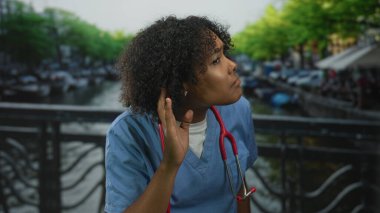 Kanal kenarında bisiklet ve demir parmaklıklarla kaplı bir caddeyi dinlemek için can atan genç Afro-Amerikan kadın doktor..