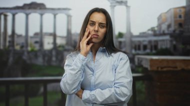 Roma harabelerinde baş ağrısı için göğüs göğüse savaşan, yanağa dokunan ve kaşlarını çatan bir kadın..
