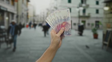 Arjantin pesolarını elinde tutan beyaz bir adam şehrin hareketli sokaklarında şehir içi yaşam arka planıyla ekonomik konsepti gözler önüne seriyor..