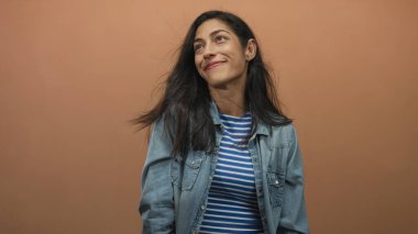 Şeftali atölyesinde saç üfleyen, kot ceket giyen ve mavi çizgili bluz giyen bir kadın..