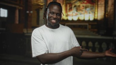 Beyaz tişörtlü, gülümseyen bir adam, kilise binasında sunağa doğru uzanan eller, arkadan bağlanmış rastalar, sıradan duruş; inanç topluluğunun neşesi.