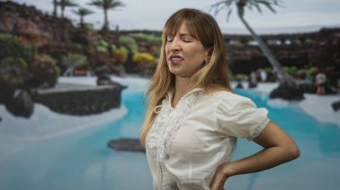 Sırtı ağrıyan genç bir kadın stüdyo ortamında mavi bir havuzun yanında sırt üstü yatıyor. Ağrı kesici..