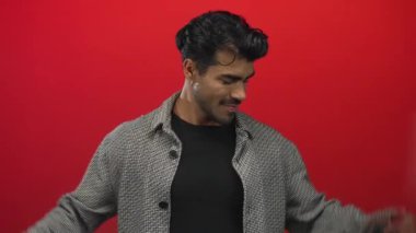 Adam, parlak kırmızı stüdyoda ringa kemiği ceketi giyerek kaslarını kasar ve yumruklarını gülümseyerek sıkar..