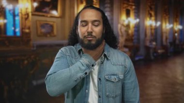 Süslü müze binasında boğulan, gözleri kapalı, kot ceketi görünür, panik acil.