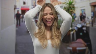 Kadın kollarını başının üstüne kaldırıyor, şehir caddesinde tavşan kulağı hareketi yapıyor, neşe dolu kahkahalar atıyor..