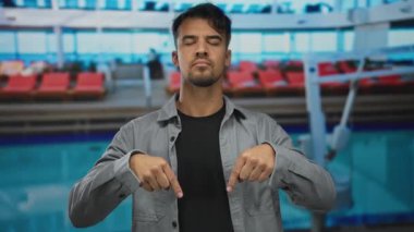 Genç bir İspanyol, açık deniz gezisi güvertesinde, açık mavi gökyüzünün altında, canlı bir havuz ve güneşli bir şezlongla çevrili, güvenle duruyor..