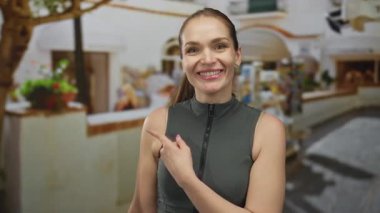 Neşeli şehir caddesinde yerel kafe dükkanını gösteren gülümseyen genç bir kadın. Neşeli bir davet..