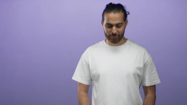 Stüdyoda mor arka planda beyaz t-shirt giyen bir adam aşağıya bakıyor; düşünceli sessiz yansıma solosu.