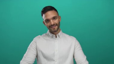 Genç İspanyol jestler yeşil bir arka plana karşı beyaz bir gömlek içinde uyur, huzurlu bir gülümseme ve kapalı gözlerle dinlenir ve rahatlar..