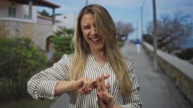 Gülümseyen ve el hareketi yapan bir kadın.