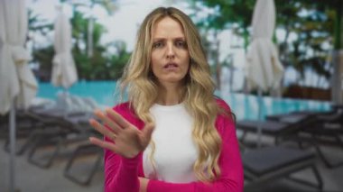 Otelin yanındaki havuz kenarındaki sarışın genç bir misafir gösterisini bir el sallamayla bitirirken, bir otelde el ele tutuşan kadın rahatsız oluyor..