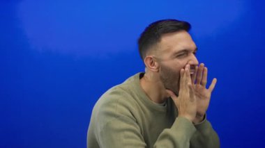 Enerjik bir adam heyecanlı mavi arka plana karşı elleri kavrulmuş bağırarak heyecan ve iletişim kuruyor.