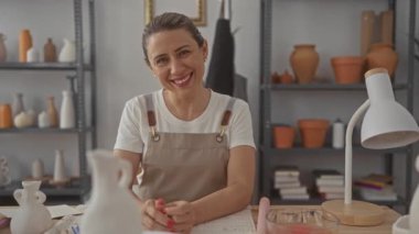 Çömlek atölyesinde çalışan gülümseyen kadın.