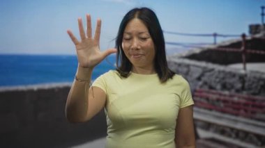 Deniz kenarındaki caddede baş parmağını gösteren bir kadın el kaldırdı ve beton parmaklıklar; özgüven kıyı ruhu.