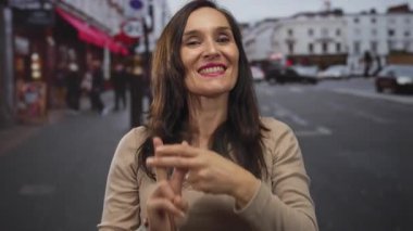 Genç bir kadın gülümsüyor ve hareketli bir şehir caddesinde hashtag 'i işaret ediyor..