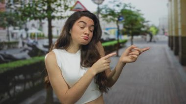 Şehir caddesindeki yapraklı ağacın altında gözleri kapalı bir şekilde başını çeviren genç bir kadın..