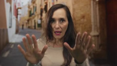 Genç İspanyol kadın, bir sokakta sakin bir jest ile avuçlarını tutar; dinginlik sükunet yansıması durgunluk.