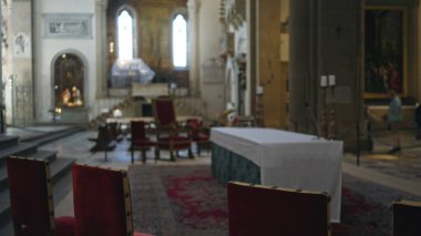 Tarihi bir katedralde yumuşak sığ bokeh aydınlatma sunağı ve kırmızı sandalyelerle bulanık kilise içi; arkaplan telif alanı sakinliği.