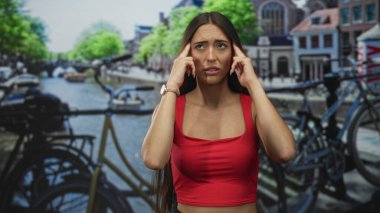 Sokak başağrısı için parmaklarını şakaklara bastıran bir kadın. Bisikletli Amsterdam Kanalı 'nda. Stres yolculuğu yorgunluğu..