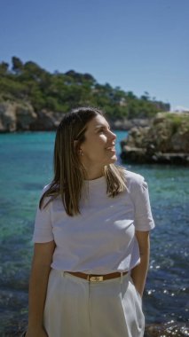 Santanyi 'de güneşli bir günde, Akdeniz' de huzur içinde gülümseyen bir kadın. Turkuaz suları ve yemyeşil arka planda yemyeşil bir yer olan Mallorca..