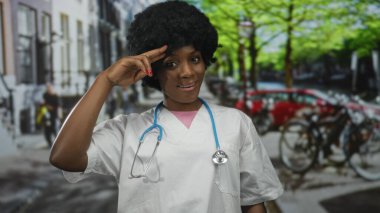 Steteskop ve beyaz önlük giyen genç kadın doktor kalabalık şehir caddesinde selam veriyor..