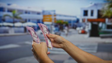 Yoğun bir caddede açık şehir ortamında Filipinli pezoları tutan eller, şehir çevresindeki mali yatırımı ve işi sembolize ediyor.