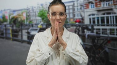 Laboratuvar önlüklü kadın bilimadamı elleri, modern caddede kanalın kenarında düşünceli bir şekilde sıkıca tutunmuştu..