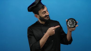 Saate bakan sakallı bir şef mavi arka planda, mutfak ortamında zaman yönetimini vurguluyor..