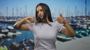 Botları ve iskelesi olan bir marinada çıplak elle baş parmak gösteren bir kadın. Kararsızlık kararı..