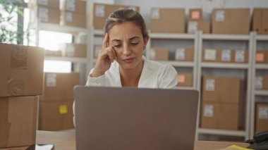 Bir binada parsel ve dizüstü bilgisayara bakarken tapınağa dokunan kadın; envanter planlama ile ilgili endişe.