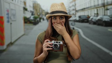 Kameralı genç bir kadın hasır şapka takarak şehir caddesinde şaşkın şaşkın dolaşırken turizm macerası ve açık havada keşif önerisinde bulundu..