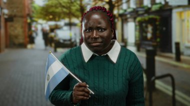 Şehir caddesinde kendine güveni tam bir Salvador bayrağı taşıyan kadın, farklı kimlikler ve açık hava ortamında uluslararası kültür karışımı sergiliyor..