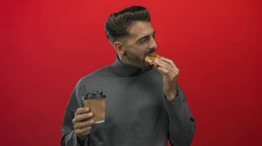 Kırmızı stüdyoda kağıt kahve bardağını tutarken waffle yiyen adam; samimi sabah tatmini.