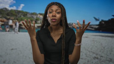 Avuç içlerini görünür halde gösteren ve kumlu sahilde saçları ören bir kadın. Düşünceli bir sohbet..