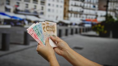 Kentsel sokak ortamında Çin Yuan banknotları tutan adam, önemli ölçüde sergilenen iş ve ekonomi kavramına odaklanıyor.