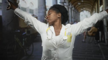 Steteskoplu kadın doktor kaldırımlı sokakta kollarını uzatıyor ve ellerini boynunun arkasına koyuyor..