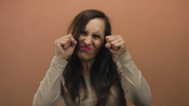 Genç İspanyol kadın yumruklarını sıkarak yüzünü buruşturuyor. Stüdyoda ağlama hareketi yapıyor. Üzüntü..