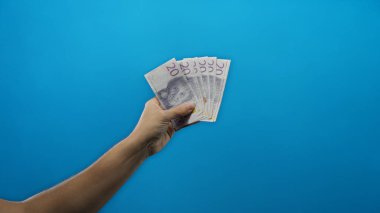 İsveç ekonomisine odaklı finansal kavramları ve döviz alışverişini sembolize eden, parlak mavi bir arkaplan önünde İsveç kronu ile el ele tutuşan bir adam..