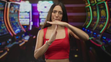 Elleri havada bir kadın kumarhane binasındaki parıldayan kumar makinelerine el kol hareketi yapıyor..