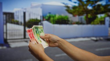 Bir şehir sokak ortamında İsrail şekellerini elinde tutan adam, şehir ortamında yatırım ve bankacılık kavramlarını vurguluyor..