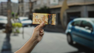 Bir şehir caddesinde, Kanada dolarlarını el ele tutuşturmak, bir adamın elinde finans ve para odaklı şehir yaşamını yakalamak..