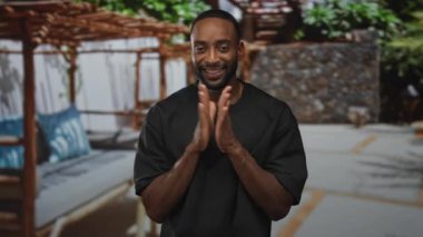 Adam gülümserken ve konuşurken dinlenme odası ve minderleri olan bir teras inşa ederek el çırpıyor; sevinç teşvik edici..