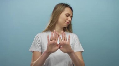 Mavi arka plana karşı ellerini kaldırarak reddeden bir kadın, bir anlık bir hoşnutsuzluk ve duyguyu yakalıyor..