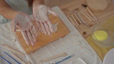 Kil kaplı kız elleri stüdyoda heykel aletleri ile ahşap tahtanın üzerinde avuç içi sunar; yaratıcılık.