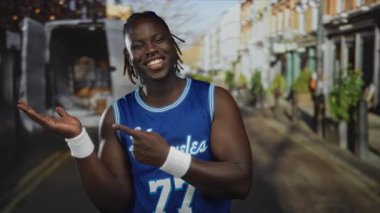 Mavi basketbol formalı adam avuç içini işaret ediyor ve şehir sokağında dağıtım minibüsüyle 