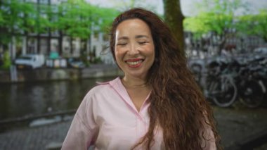 Görünür bir yüz ve uzun saçlı bir cadde üzerinde gülümseyen bir kadın, neşe rahatlatıcı bir memnuniyet.