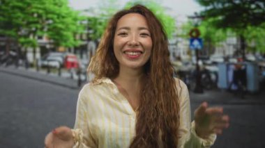 Elleri göğsünde ve çapraz kollu bir kadın şehir caddesinde bisiklet ve binaların yanında bir jest yapıyor..