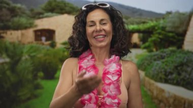 Bikini giyen İspanyol kadın parkta el kamerasına uzanıyor; davetiye bağlantısı sıcak karşılanıyor.