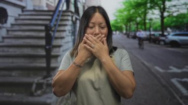 Sokakta ağzı taş basamaklarla kaplı bir kadın ve park etmiş arabalar, önlük ve bilezik takan; sessizlik..